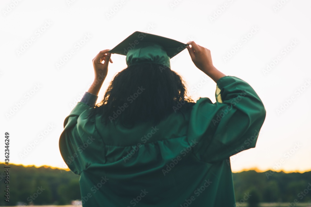 Φωτογραφία Young woman in a green academic dress holding a gown cap - the concept of gradua