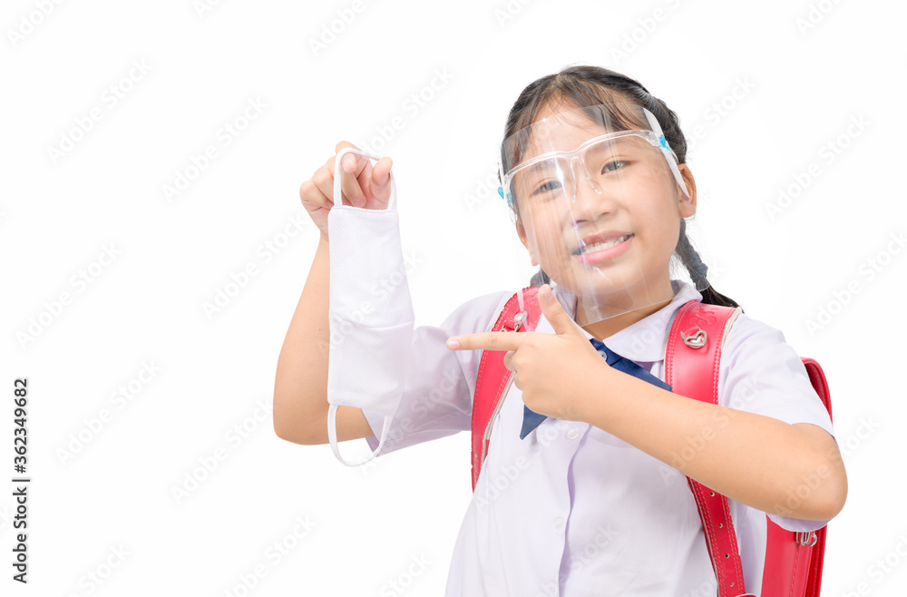 Cute schoolgirl wear uniform and face shield and points to the cloth mask isolated Cute schoolgirl wear uniform and face shield and points to the cloth mask isolated