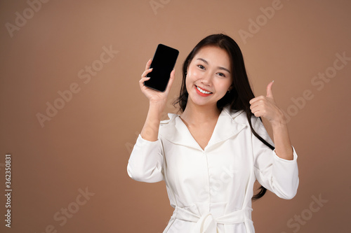 Asian business woman recommended smartphone apps for internet marketing, Business casual outfit, isolated with mocha brown background