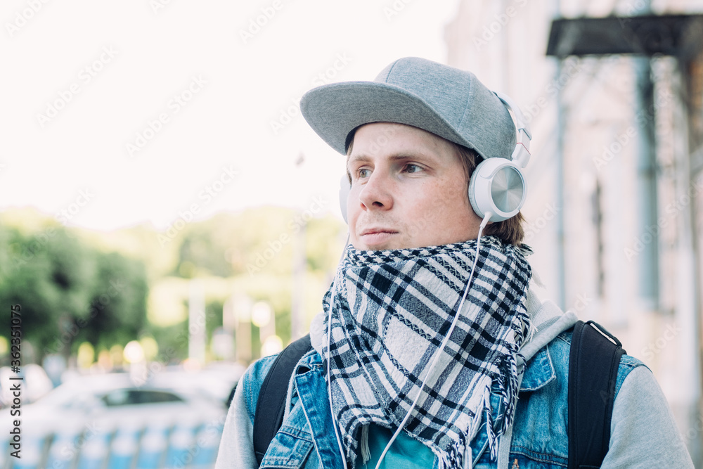 Caucasian man in headphones listens to music and walks around the city