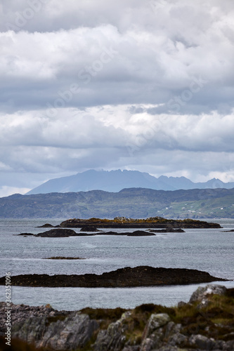 Distant mountain over the sea Scottish Highlands Scotland on a cloudy day with rocks in foreground 