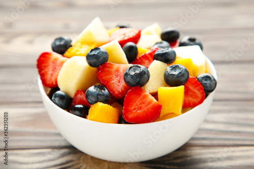 Salad with fresh fruits and berries on brown wooden background