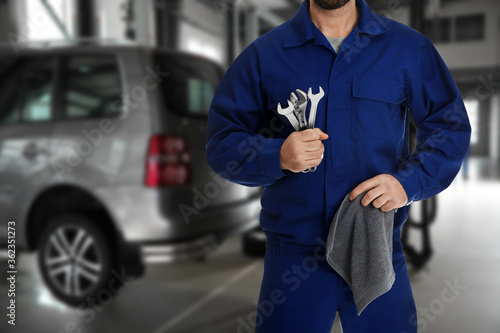 Professional mechanic with wrenches and rag at tire shop, closeup
