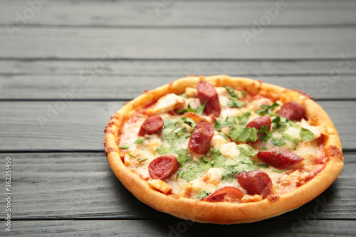 Tasty Italian pizza with sausage on black wooden table with copy space