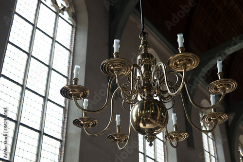 Copper Chandelier with candles hangs in front of a window in the Grote Kerk in Monnickendam