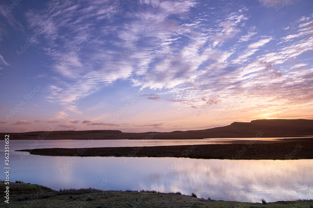 Silhouette of land between water on isle of sky Scotland Scottish highlands with water in foreground at sunset Silhouette of land between water on isle of sky Scotland Scottish highlands with water in foreground at sunset