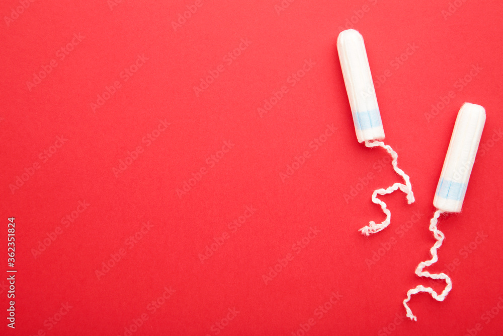 Menstrual tampons on a red background. Cotton tampon for women with copy space Menstrual tampons on a red background. Cotton tampon for women with copy space