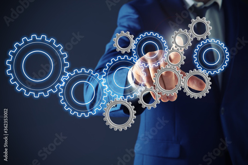 Εκτύπωση καμβά Businessman touching gear mechanism on dark background, closeup