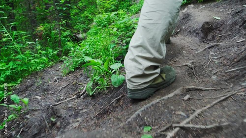 Man Hiking Outdoors alont Path in theForest. Male Adult Trekking in the Woods. Back Close Up View of Feet in Trail Shoes photo