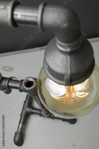Retro lamp made of metal water pipes with an Edison lamp on a gray background. The concept is a good idea.