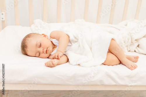 Small baby girl 6 months old sleeping in a white bed, healthy baby sleep