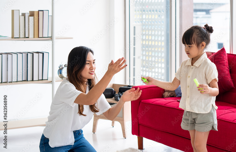 Fototapeta premium asian mother playing blowing bubbles with her young daughter in the living room in the summer. family together and relationship