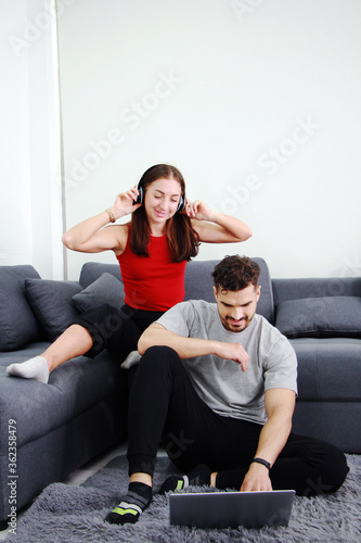 Smiling Caucasian Couple love relaxing with headphones and listening to music with laptop in social media online on sofa. Technology and Married family lifestyle on holiday Concept.