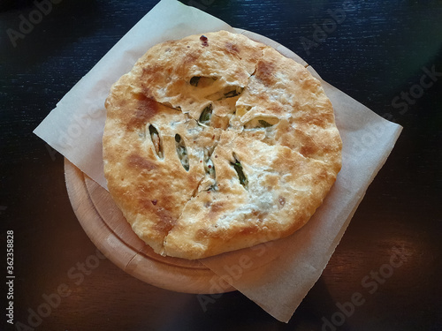 Khachapuri with spinach and cheese traditional Georgian food, wooden dark rustic background. Food photo