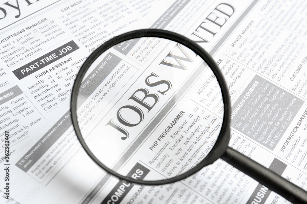Looking through magnifying glass at newspaper, closeup. Job search concept Looking through magnifying glass at newspaper, closeup. Job search concept