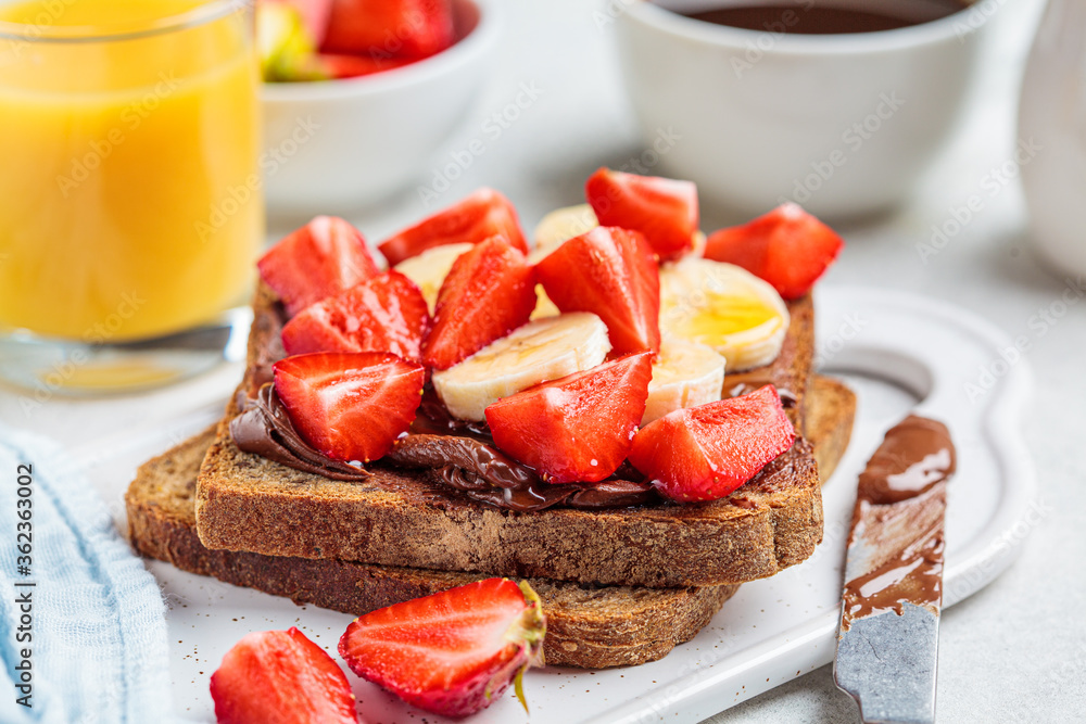 Toast with chocolate hazelnut spread, banana and strawberries for breakfast. Breakfast food concept. Toast with chocolate hazelnut spread, banana and strawberries for breakfast. Breakfast food concept.