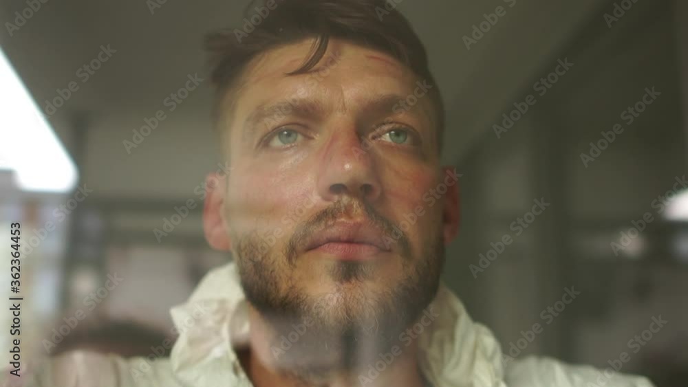 Close portrait of a tired doctor in a protective suit behind a protective glass in a hospital ward. Red prints from the mask are visible on the face. Medicine during the epidemic of coronavirus Close portrait of a tired doctor in a protective suit behind a protective glass in a hospital ward. Red prints from the mask are visible on the face. Medicine during the epidemic of coronavirus