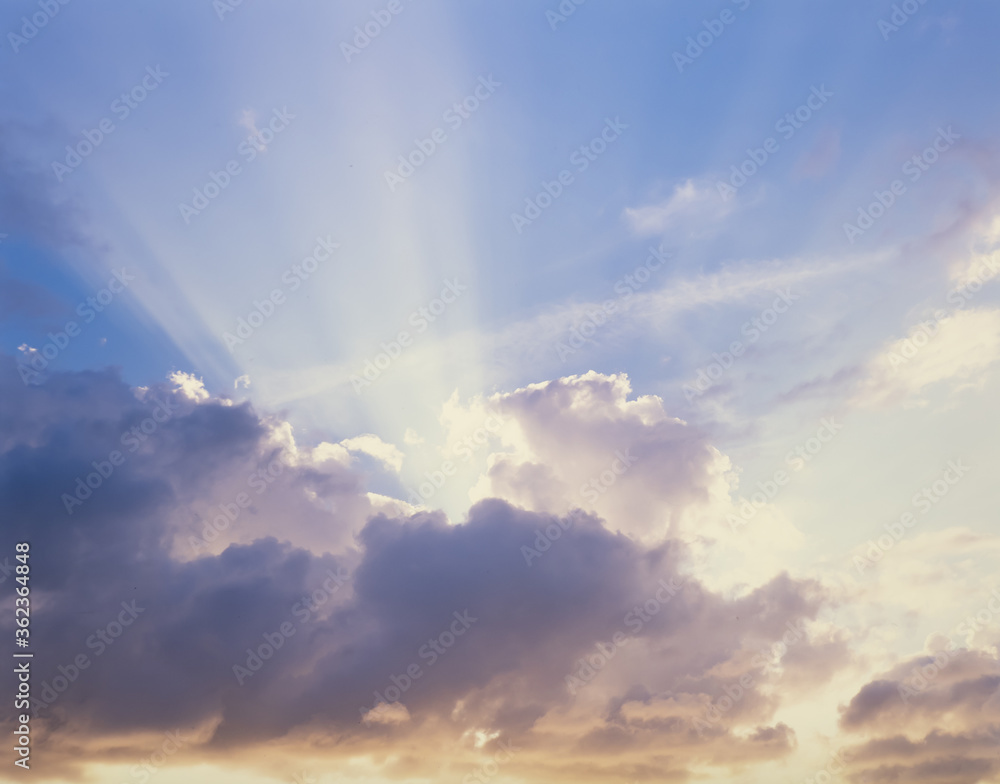 Sun rays coming out from behind clouds with blue sky above Sun rays coming out from behind clouds with blue sky above