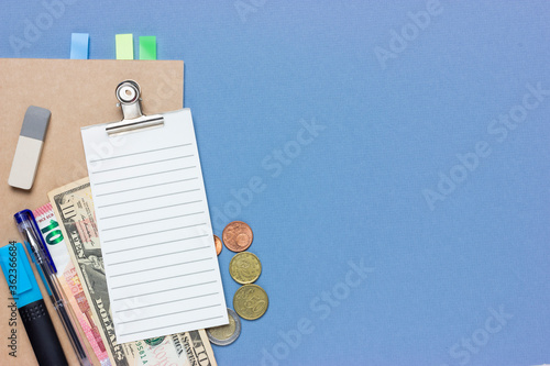 Concept collage on a financial theme. Planning a budget or shopping. Checklist, coins, 10 euros, dollar, coins, stationery. Blue background and place for text.