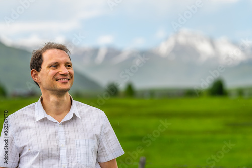 Crested Butte, Colorado countryside with happy man standing by rural fence in summer on cloudy day with green grass and mountain view