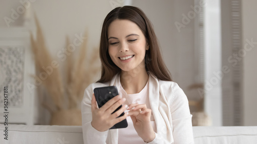 Close up smiling beautiful woman looking at smartphone screen, happy satisfied girl holding phone, chatting in social network, shopping online, browsing mobile device apps, searching information