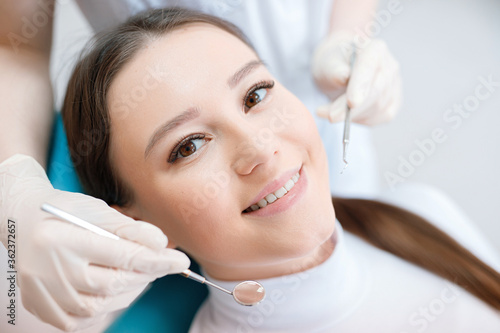 Patient in dental chair. Dentist s hands in gloves work with a dental tools. Beautiful young woman having dental treatment at dentist s office.