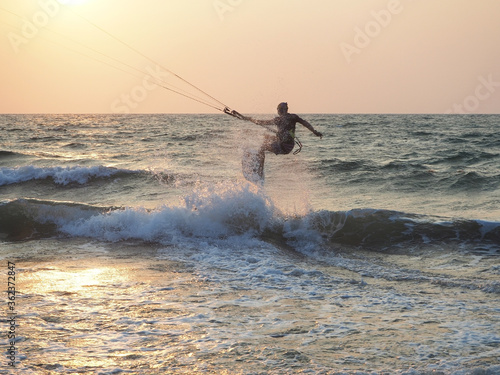 India, Goa, Arambol, a man kitesurfing near the coast at sunset