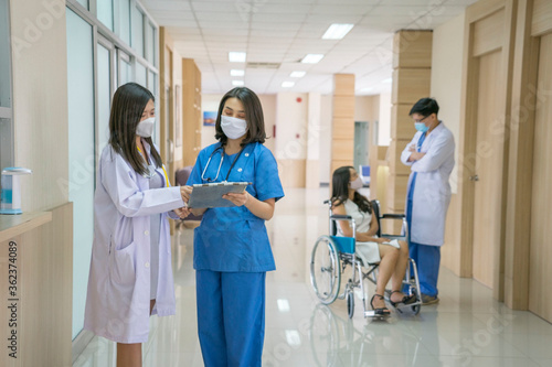 In the hospital environment, the doctor wears the adhesive shirt, discuss with the surgeon and nurse talking inquire about the wheelchair patient in front of the dispensing room.