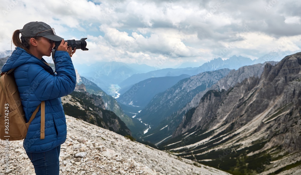 Woman taking pictures with camera while hiking.