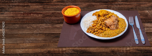 Delicious Caruru. Traditional Afro-Brazilian dish made with okra and dried shrimp, accompanied by vatapa, beans, rice, chicken and farofa. On a wooden table. photo