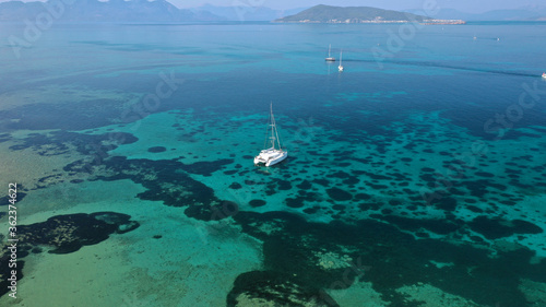 Aerial drone photo of catamaran sailing yacht anchored in tropical exotic emerald sea coral reef bay
