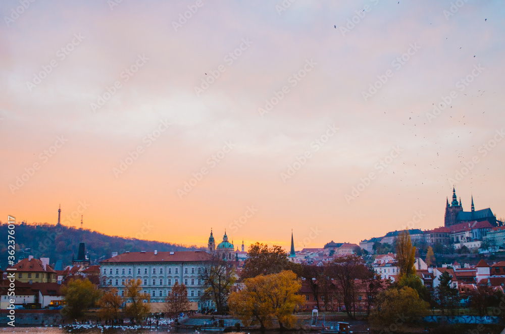 Dramatic sundown with a panoramic view of the other side of Prague in the autumn and a gradient of orange to pink colors in the cloudy sky.