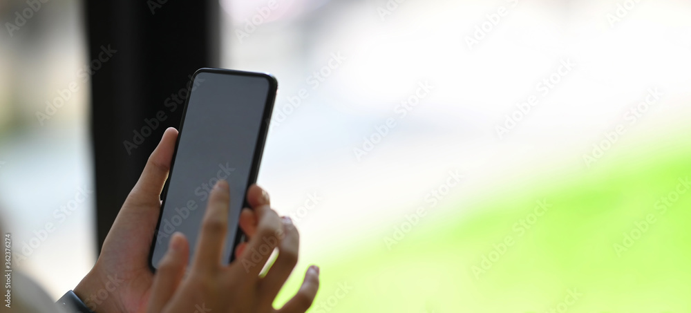Closeup woman hands are using a white blank screen smartphone in the living room. Closeup woman hands are using a white blank screen smartphone in the living room.