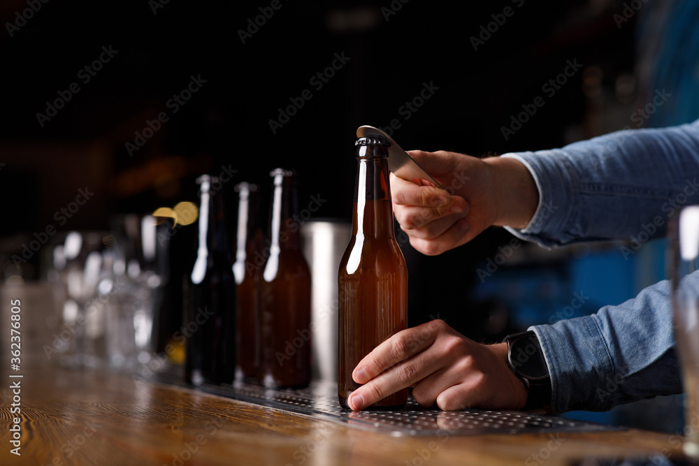 Customer service in pub. Bartender hands open bottle of beer at bar