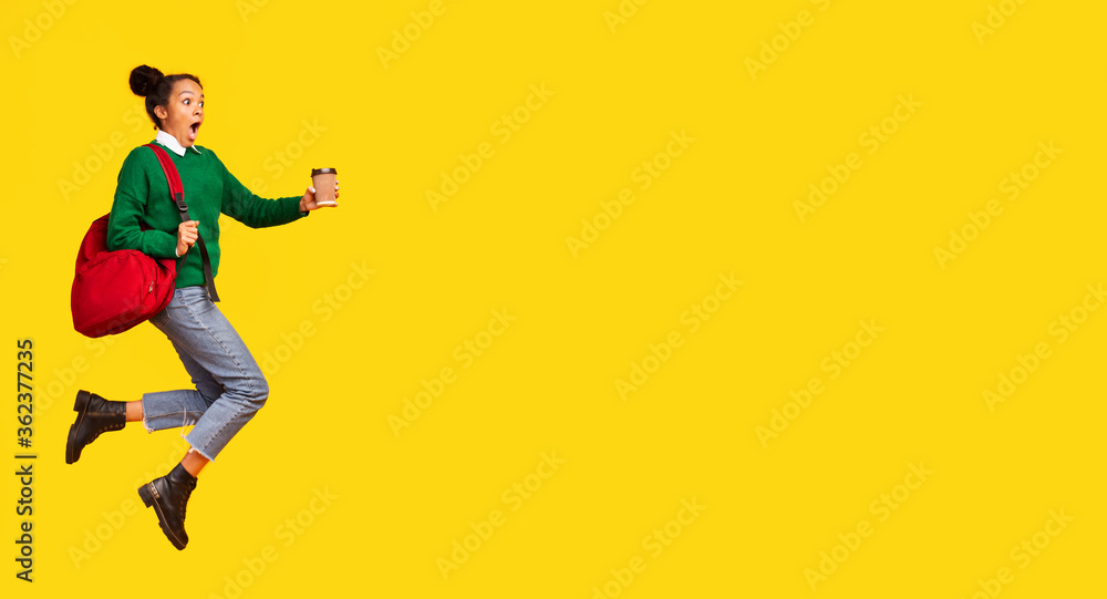 Afro girl jumping in hurry over yellow background