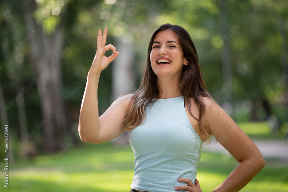 Portrait of laughing beautiful Turkish young woman makes okay gesture, indicates agreement and that everything is fine, with warm and positive mood, awesome emotions. Gestures and emotions concept.. Portrait of laughing beautiful Turkish young woman makes okay gesture, indicates agreement and that everything is fine, with warm and positive mood, awesome emotions. Gestures and emotions concept..