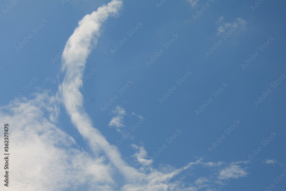 wispy white cloud in the shape of the letter C, in a blue sky wispy white cloud in the shape of the letter C, in a blue sky