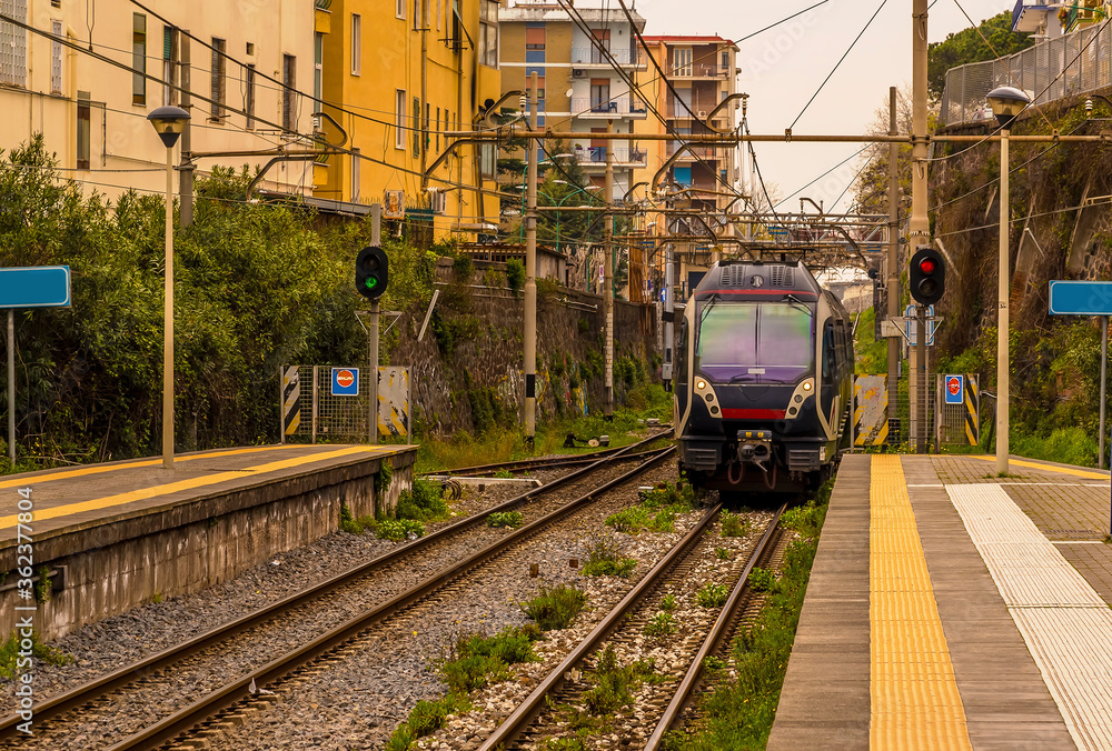 Fototapeta premium A view down a platform with a train approaching on the railway line between Naples and Sorrento, Italy