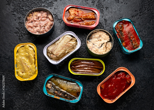 Canned fish with different assortment types of seafood on rustic stone background.