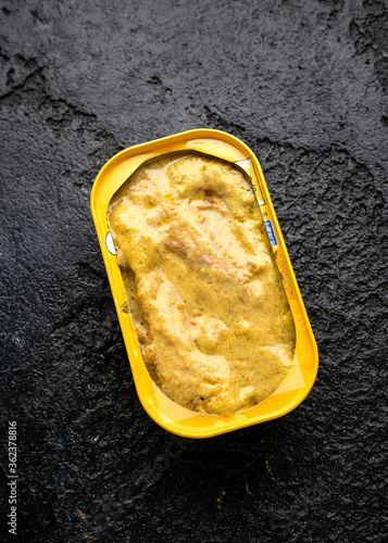 Canned Mackerel fish in curry sauce on rustic stone background.