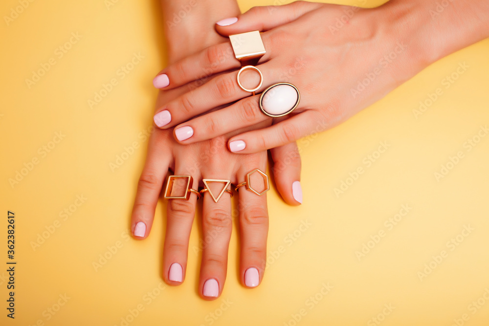 Fototapeta woman hands with manicure and jewelry ring on yellow background, beauty style concept