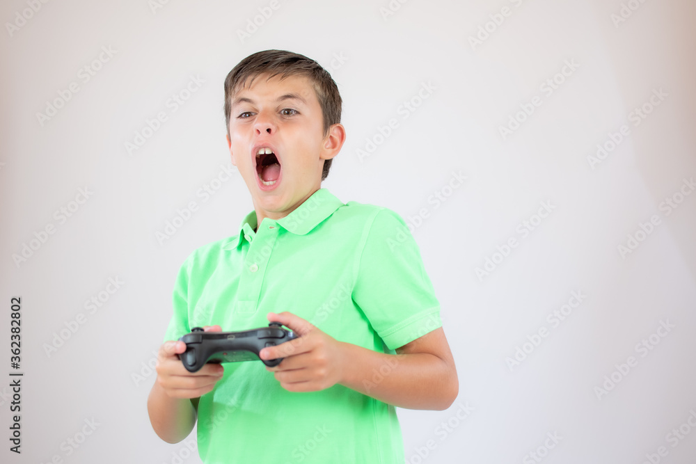 Little boy with green polo shirt concentrated with the game controller Little boy with green polo shirt concentrated with the game controller