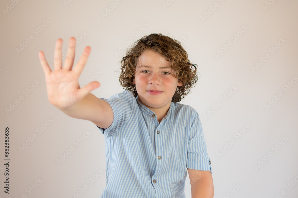 Boy with blue shirt smiling and making stop gesture Boy with blue shirt smiling and making stop gesture