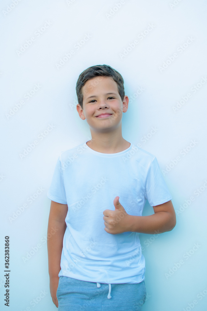 Handsome little boy with white shirt smiling on white wall background Handsome little boy with white shirt smiling on white wall background