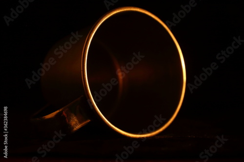 aluminum mug, circular detail with warm light and dark background. minimalist and elegant
