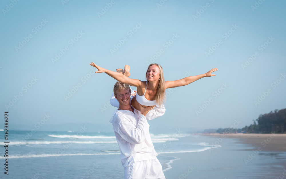 guy holds in his hands a girl in white clothes on the ocean guy holds in his hands a girl in white clothes on the ocean