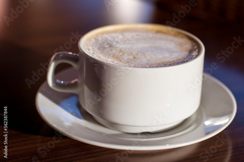 A large cup of latte coffee with milk froth on a table in a cafe. Food and drink for breakfast.