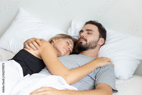 Young cute couple hug and sleep together in bed