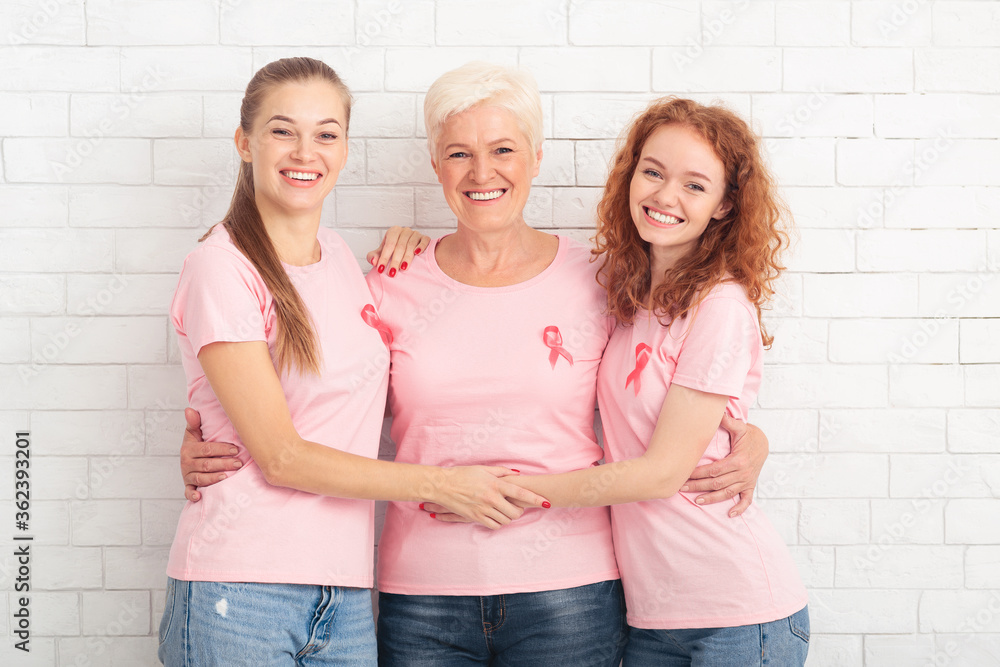 Obraz premium Three Breast Cancer Volunteers Ladies Hugging Over White Background