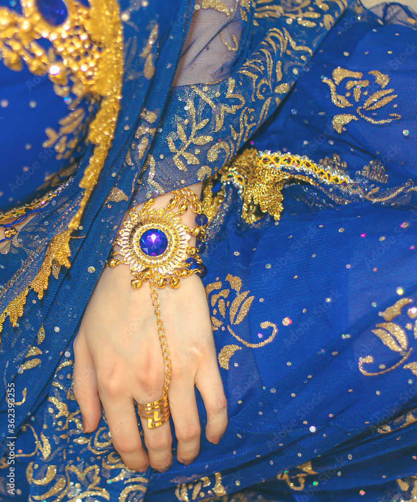 Obraz premium Indian woman cosplay. Young beautiful woman in blue indian sari dress closeup on the multicolored brown background. Body parts